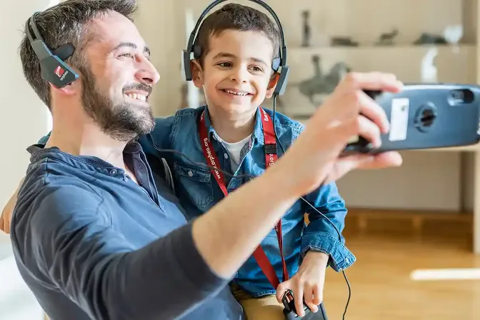 Vader en zoon met hoofdtelefoons maken een selfie tijdens een audiotour