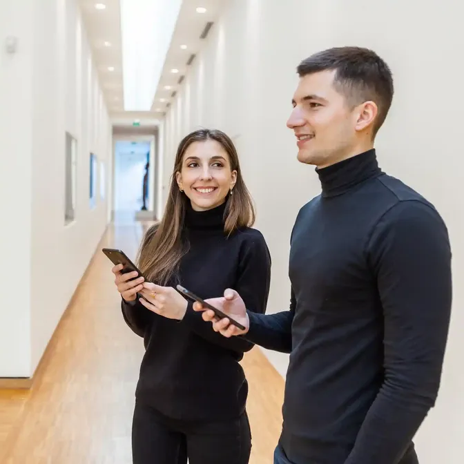 Twee bezoekers gebruiken een museumapp op hun smartphone