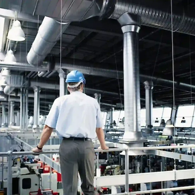 Bezoeker met helm tijdens een fabrieksrondleiding met fluisterset